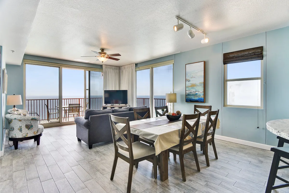 A bright, inviting open-concept space featuring a dining table, sofa, TV, and large windows overlooking the sea. The arrangement is perfect for hosting dinners, movie nights, or simply enjoying the view, with plenty of seating for family and friends.